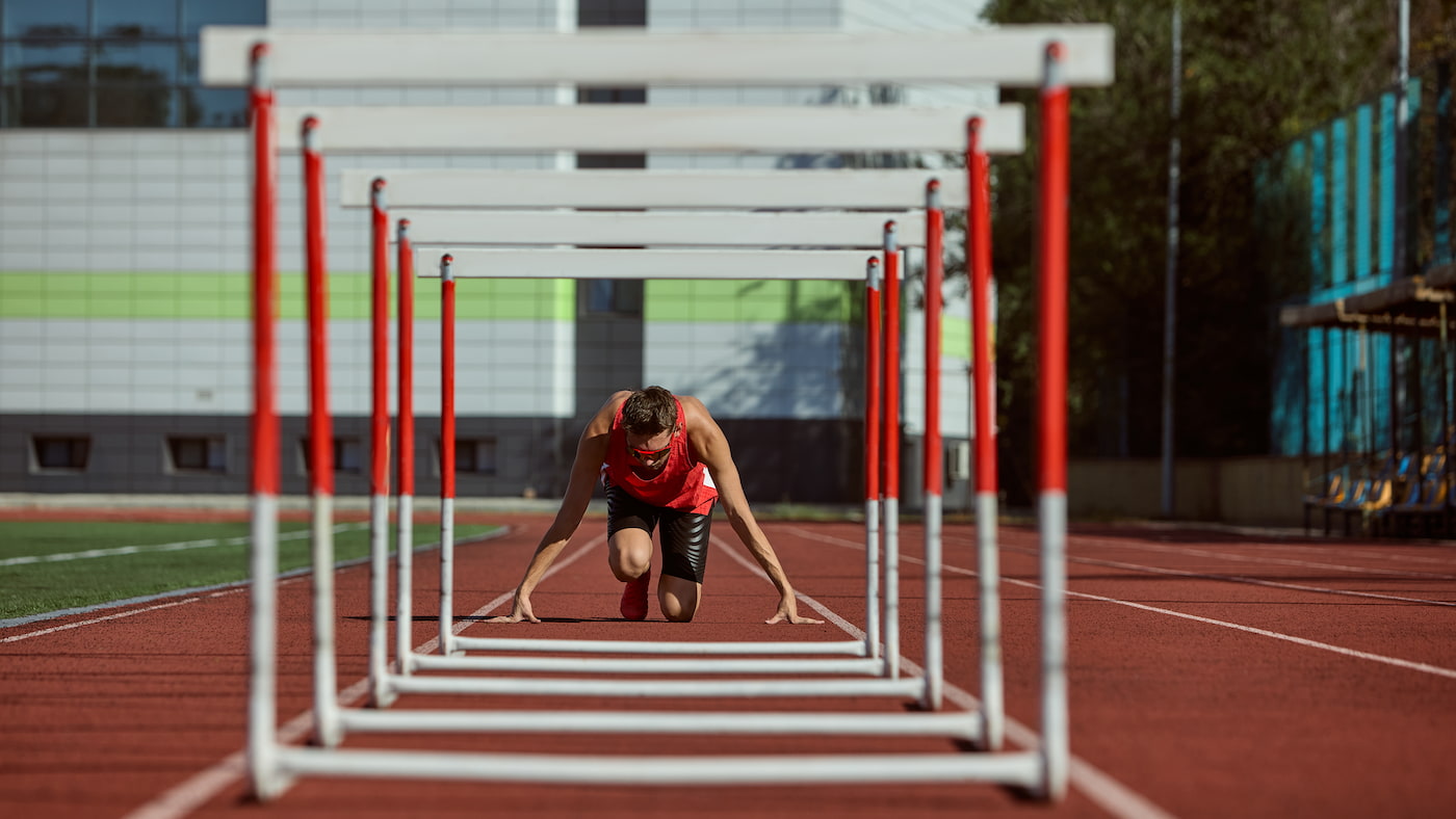 Ein Hürdenläufer vor den Hürden in Startposition als Symbol für die PR Branche in den Startlöchern zum Umbruch