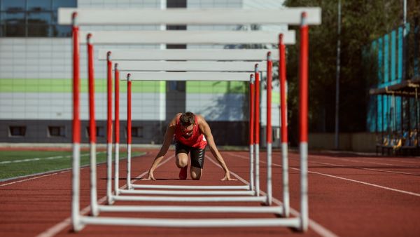 Ein Hürdenläufer vor den Hürden in Startposition als Symbol für die PR Branche in den Startlöchern zum Umbruch