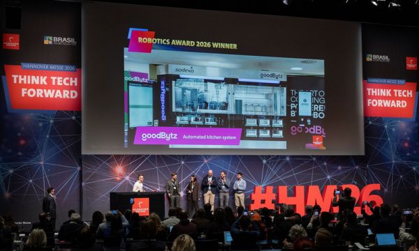 Auf einer Bühne stehen sechs Personen nebeneinander und posieren für ein Foto. Zwei von ihnen halten eine transparente Trophäe. Über ihnen ist eine Leinwand mit Foto von einem automatisierten Küchensystem zu sehen von goodBytz und einem mit dem Hinweis auf den Gewinn des  Robotics Awards. Im Vordergrund sind Zuschauer zu sehen, einige fotografieren die Szene mit ihren Smartphones.
