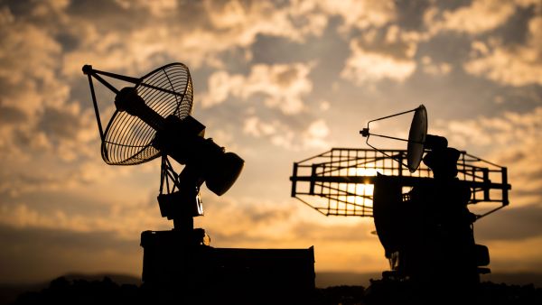 Silhouetten von zwei Radarantennen vor einem Sonnenuntergang, Symbol für Kommunikation und Verteidigungsfähigkeit – im Kontext der Studie von Fink & Fuchs zur sicherheitspolitischen Neuausrichtung.